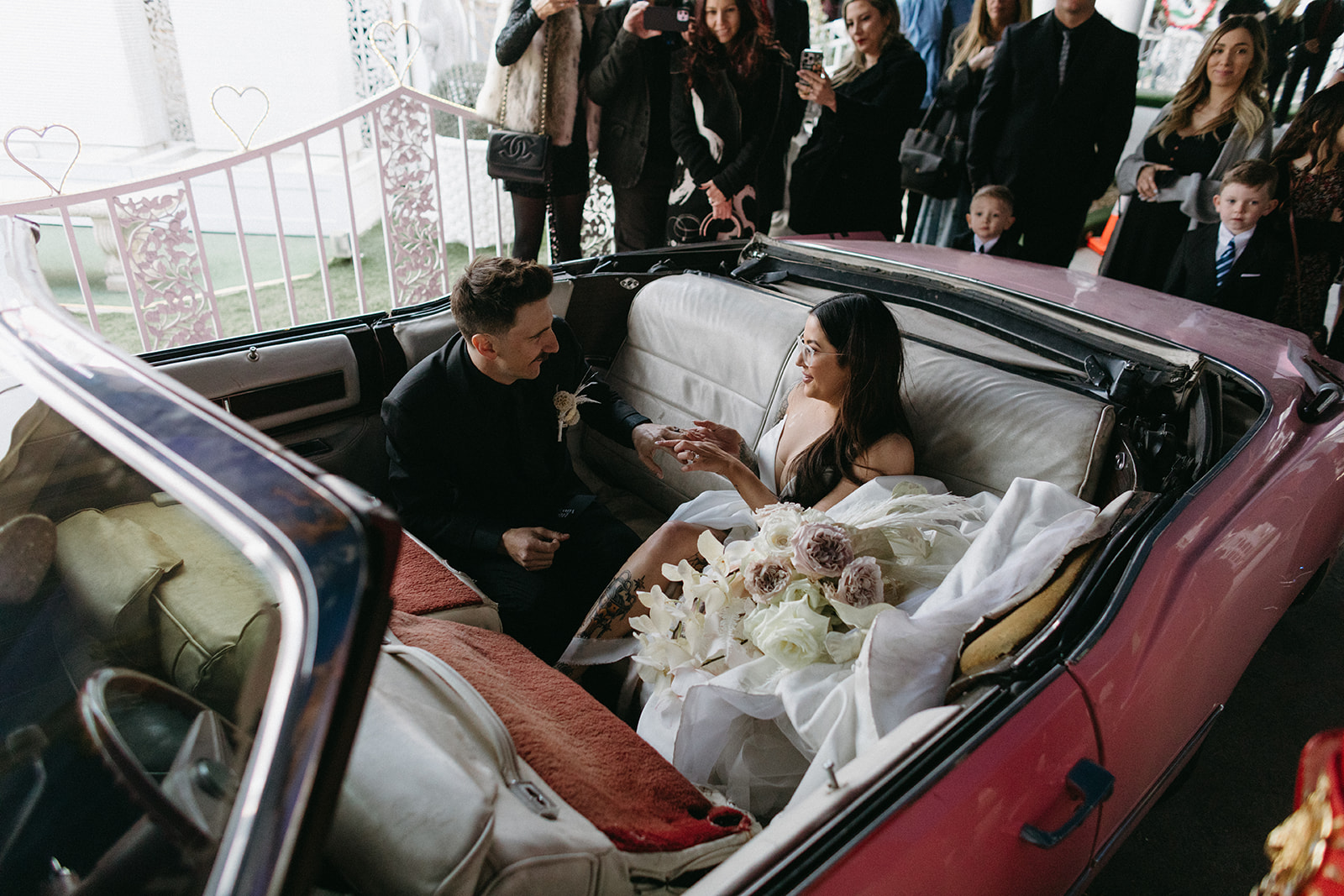 Bride putting on Groom's Wedding Ring During Ceremony in Pink Cadillac 