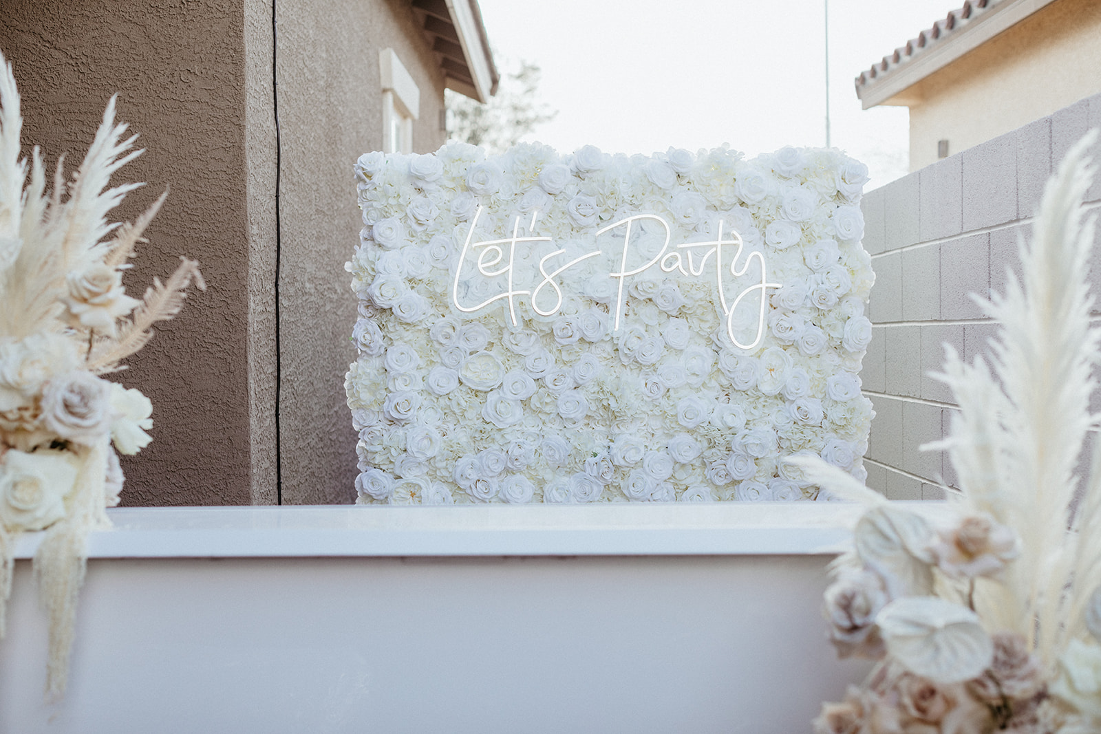 White Flower Wall and Let's Party Neon Sign for Las Vegas Backyard Wedding Reception 