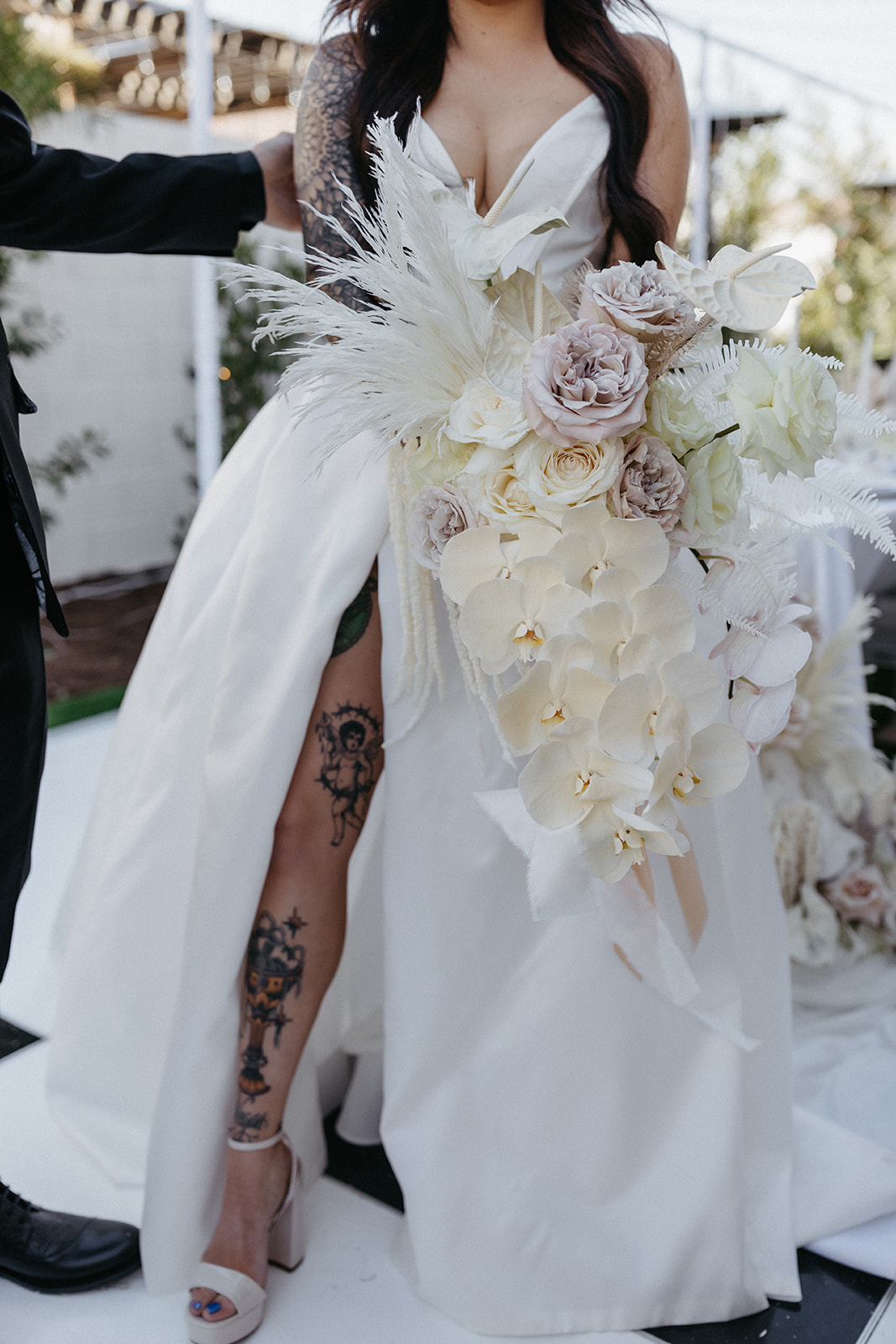 Bride in White Dress with Slit and Block Heels Standing with Monochromatic Modern Bouquet with White Orchids 