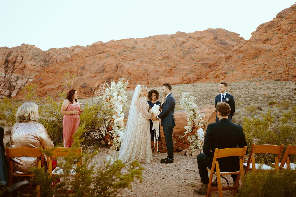 Bride and groom at the altar in between the asymmetrical flower arches in front of the red rocks of ash springs.