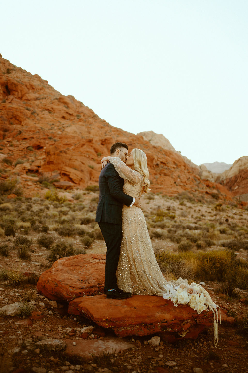 Newlyweds kissing on the rocks in the middle of ash springs, red rock. 