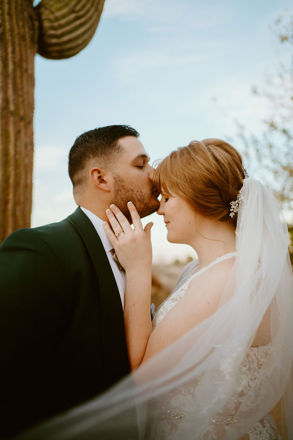 Groom kissing Brides forehead near cactus 