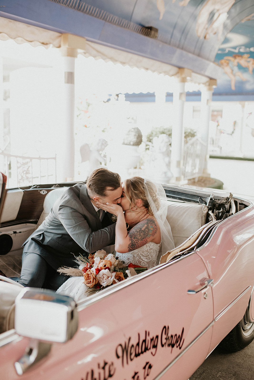 First Stop! A Little White Chapel Bride and groom share a kiss inside the pink Cadillac.