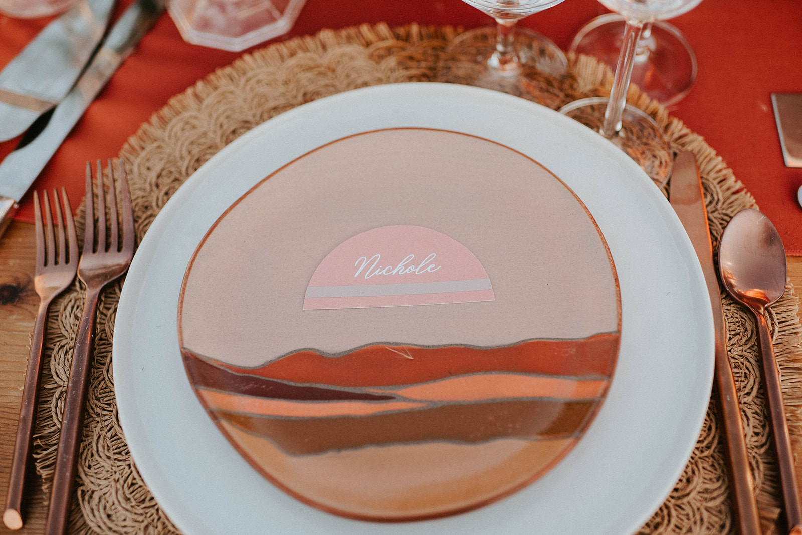 Boho styled plate decorated to look like mountains with name tag placed. Bronze utensils 