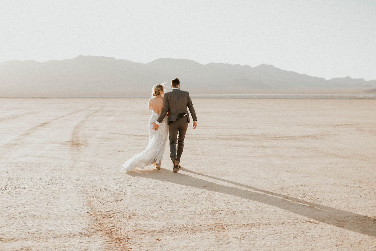 First Stop! A Little White Chapel bride and groom walking in the desert. Groom giving his bride a little squeeze. 