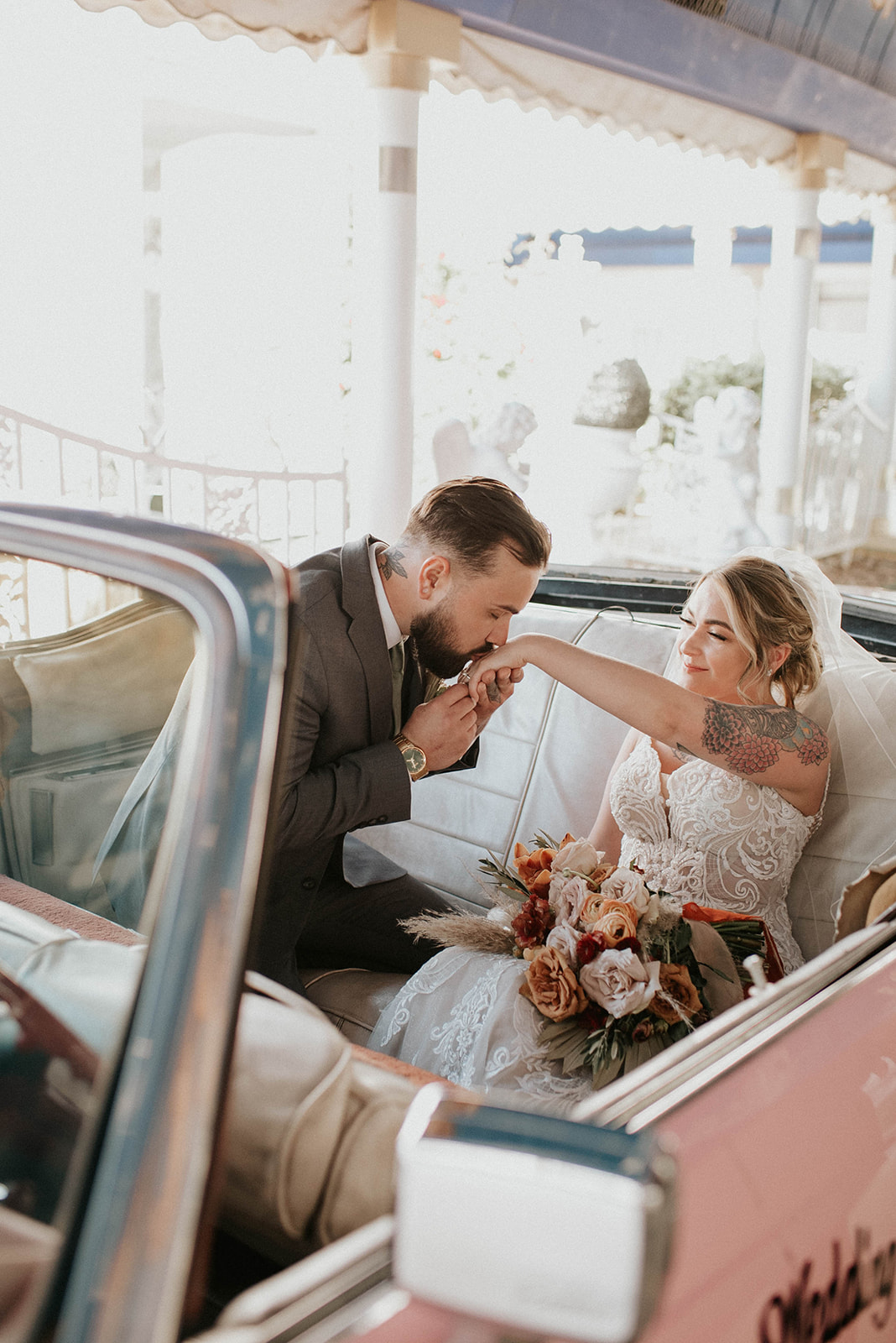 First Stop! A Little White Chapel groom kisses the brides hand inside the pink Cadillac. 
