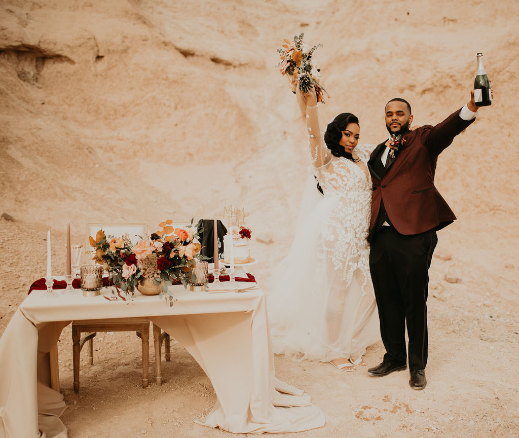 Fossil Beds Sunset Elopement the new newlyweds cheering with champagne next to the blush sweetheart table at fossil beds