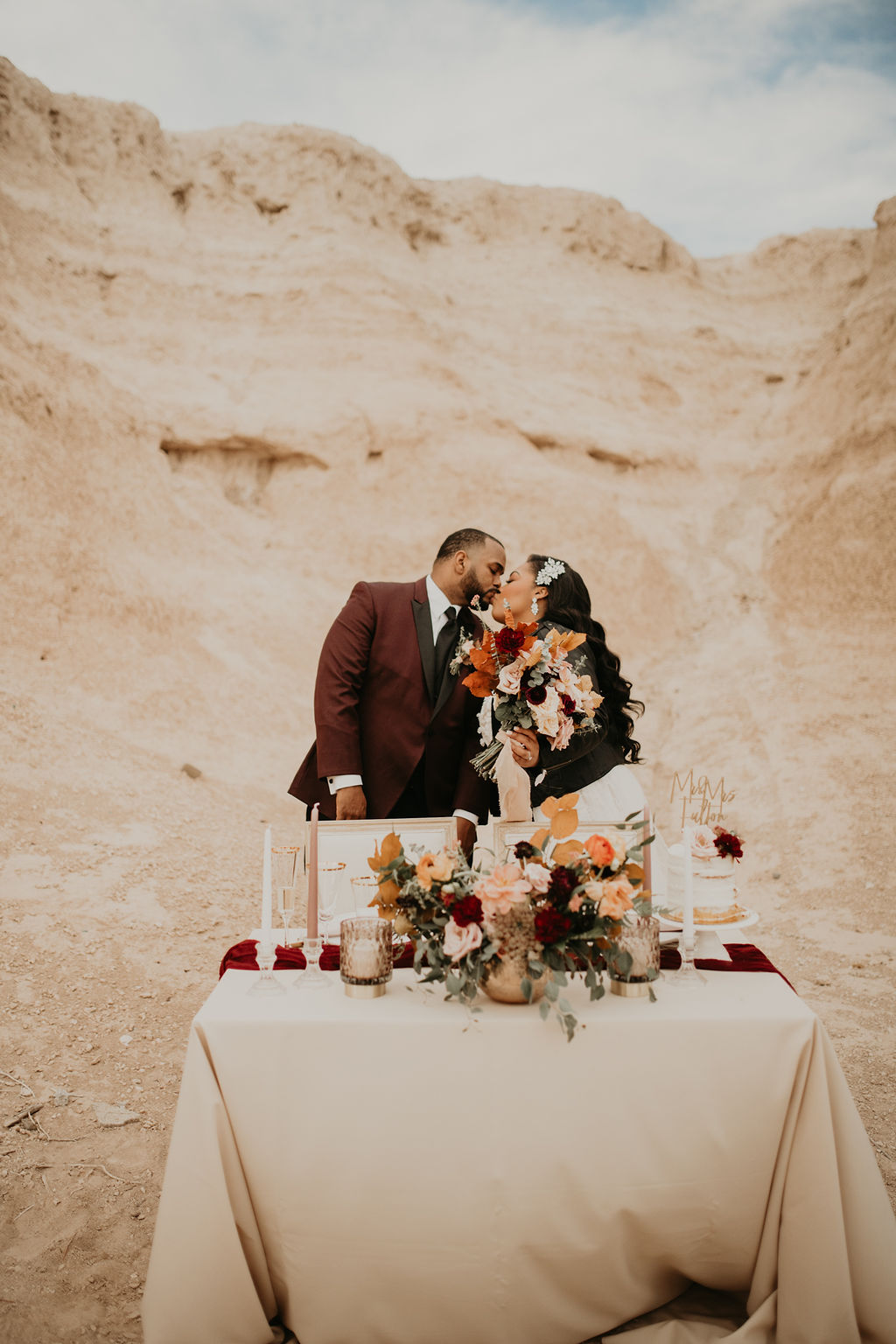 Newlyweds kissing behind the gold sweetheart table.