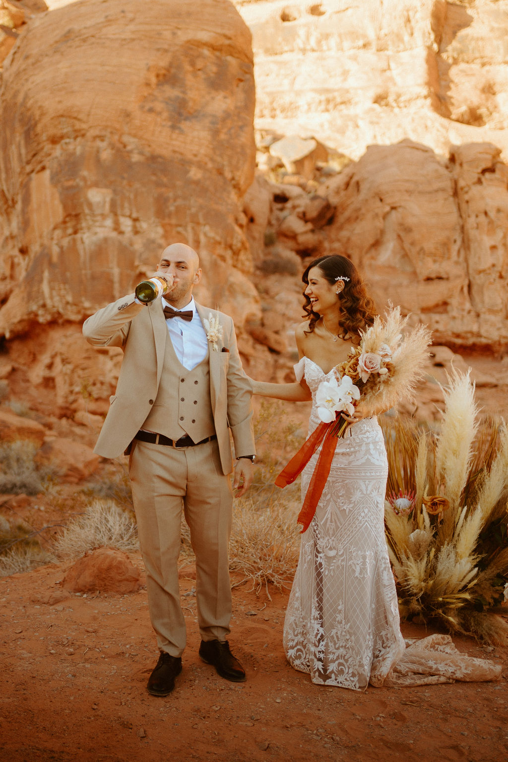 Groom celebrating with Champagne during elopement. International Couples! Welcome to the desert!