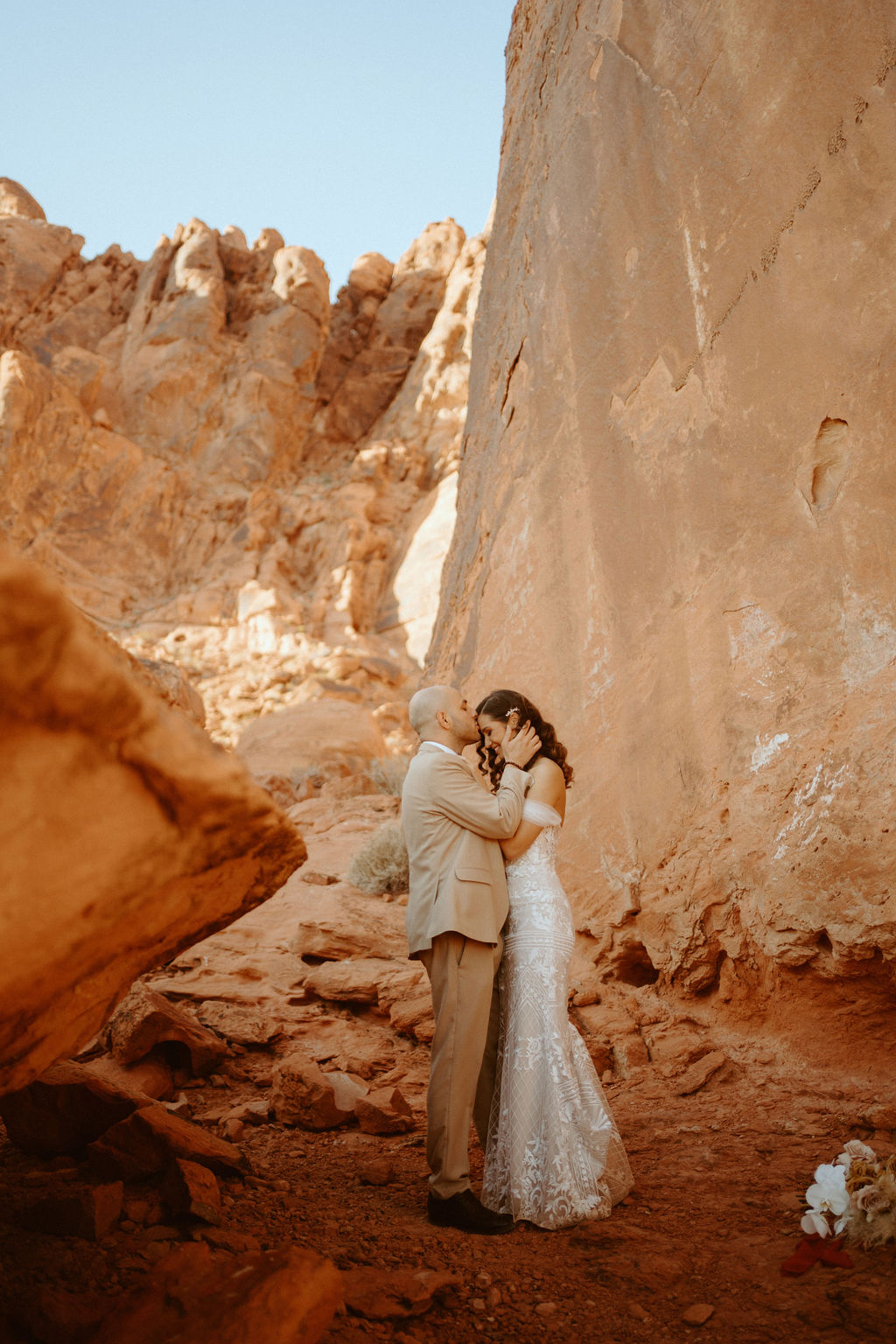 Groom kissing brides forehead under dramatic Valley of Fire rocks 