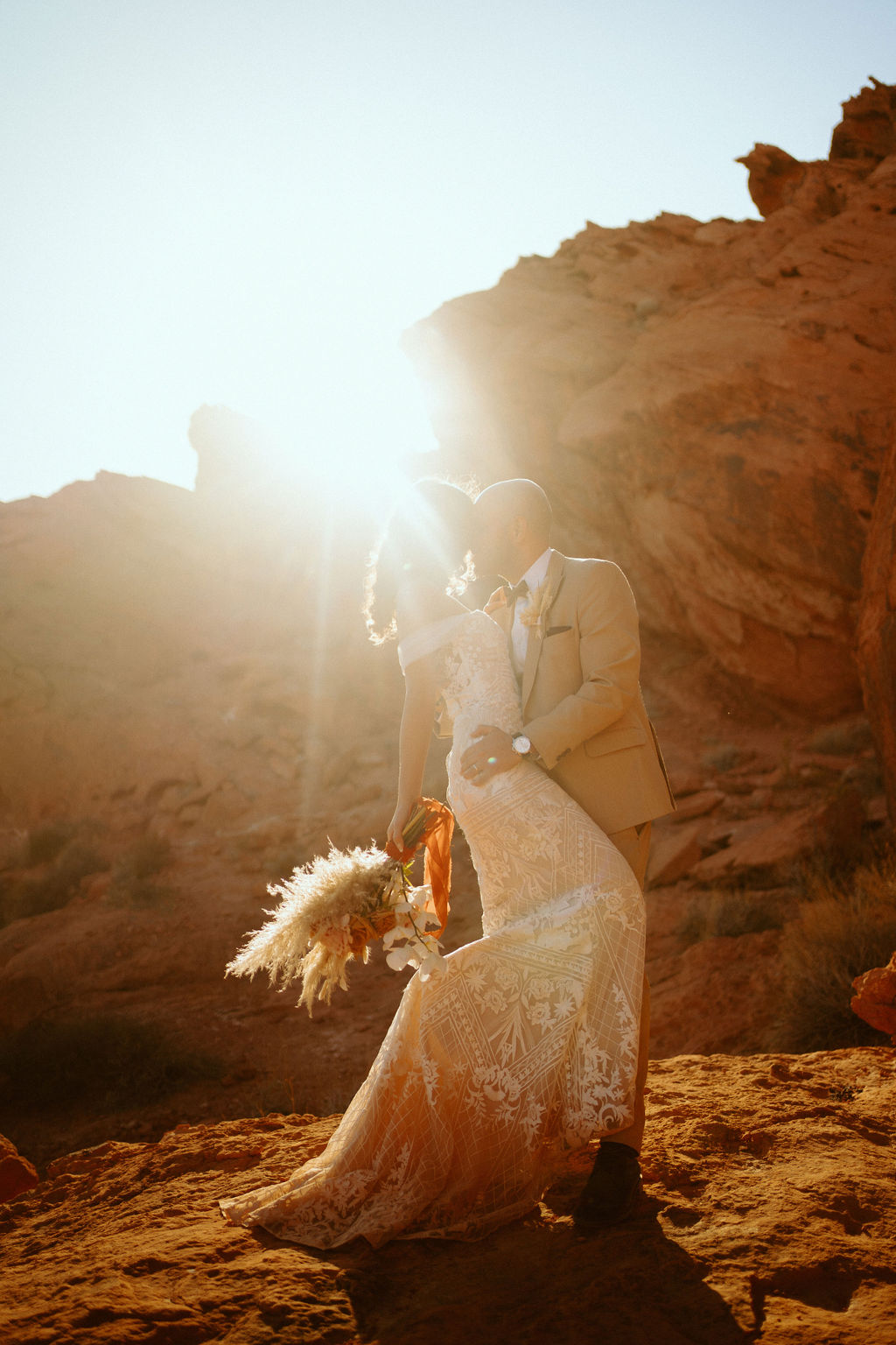 Sun setting behind newlyweds in desert 