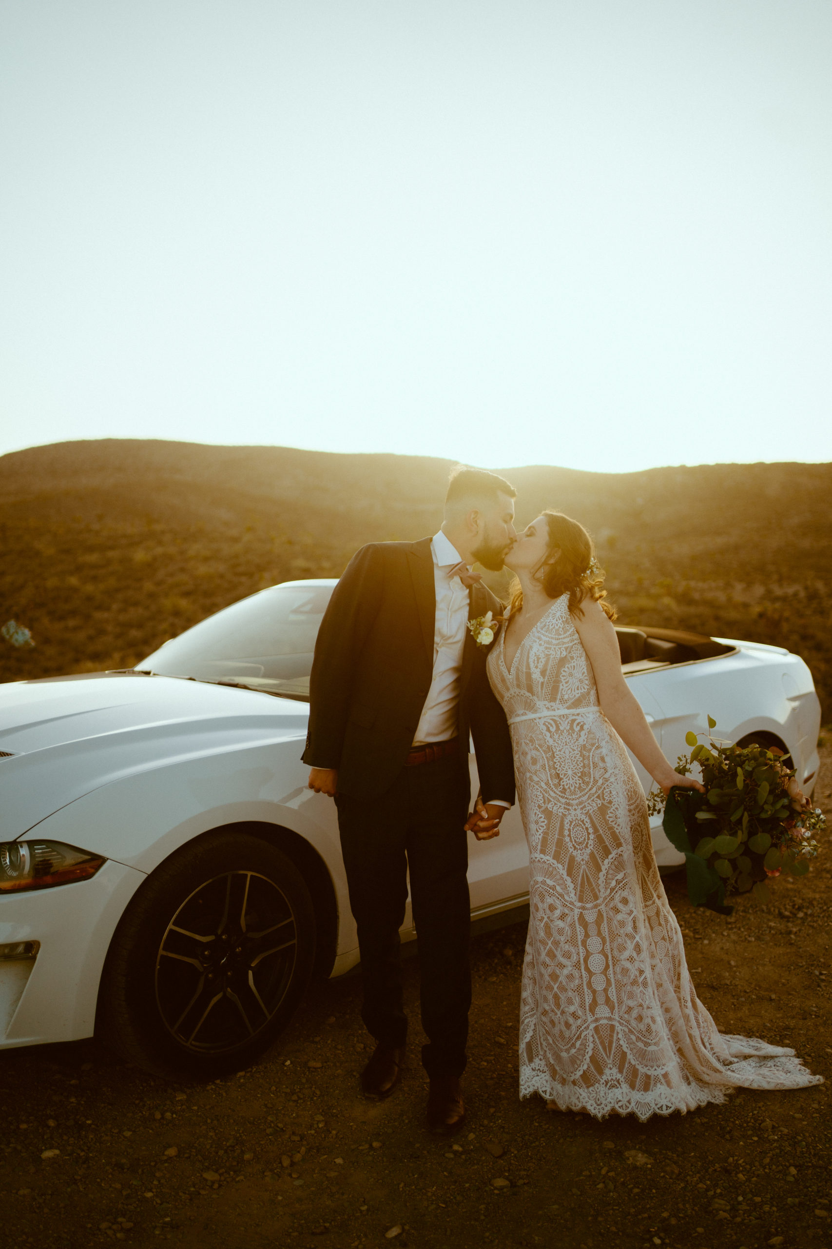 Bride in lace dress with groom next to Mustang 