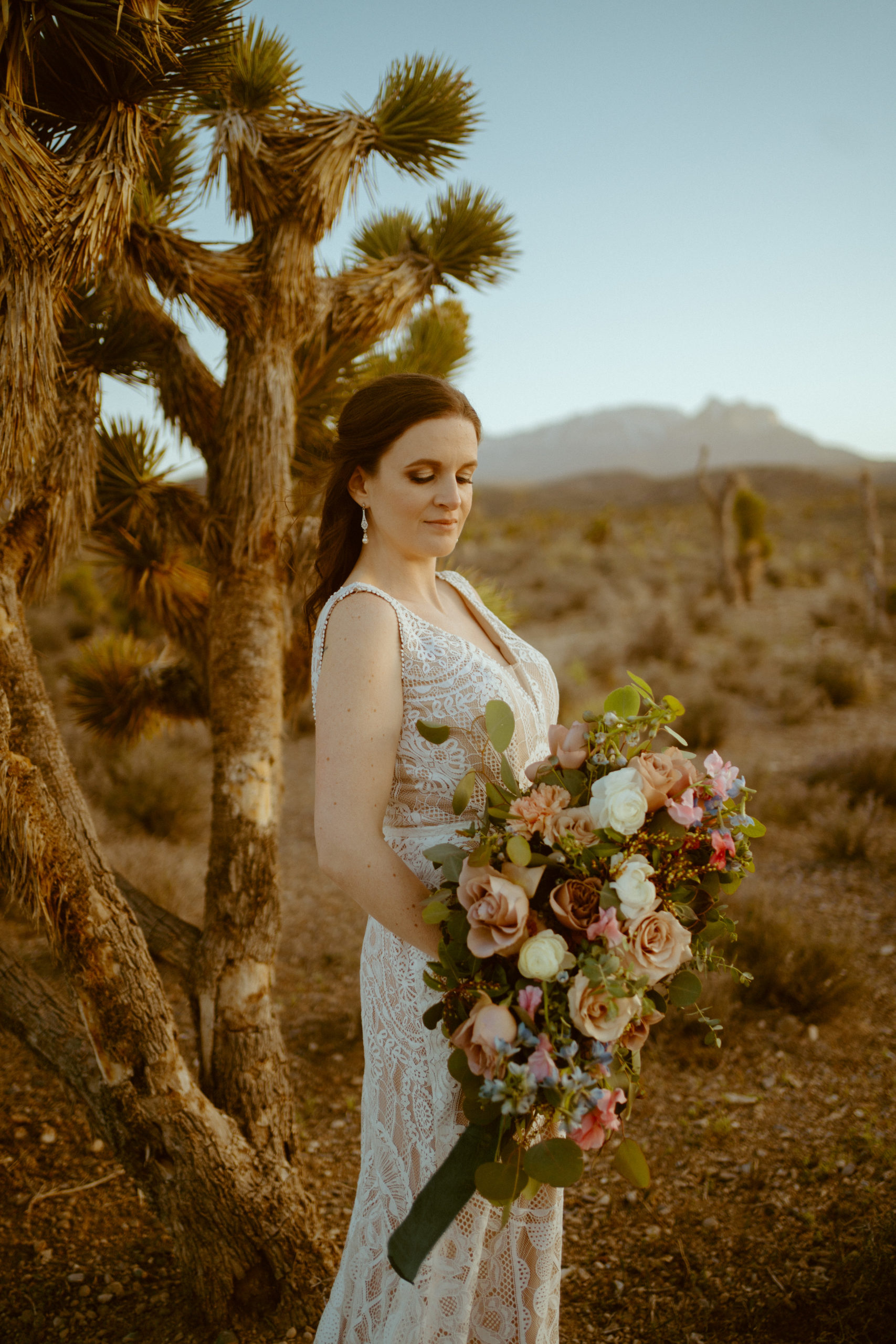 Bride holding bouquet with dusty florals with pink, blues, greens 