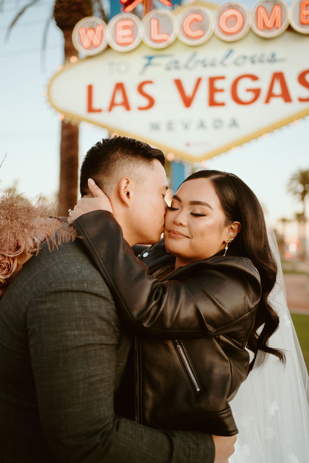 Groom Kissing Bride's Cheek in front of Famous Las Vegas Sign 