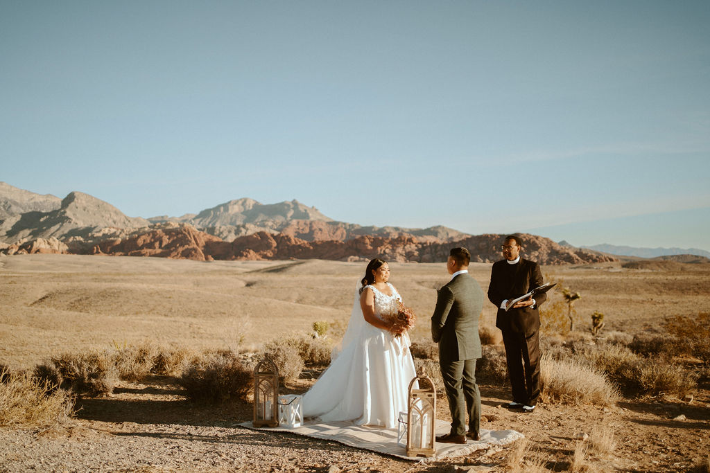 Couple getting eloped and standing on Rug with Lanterns and Red Rock Canyon in the background