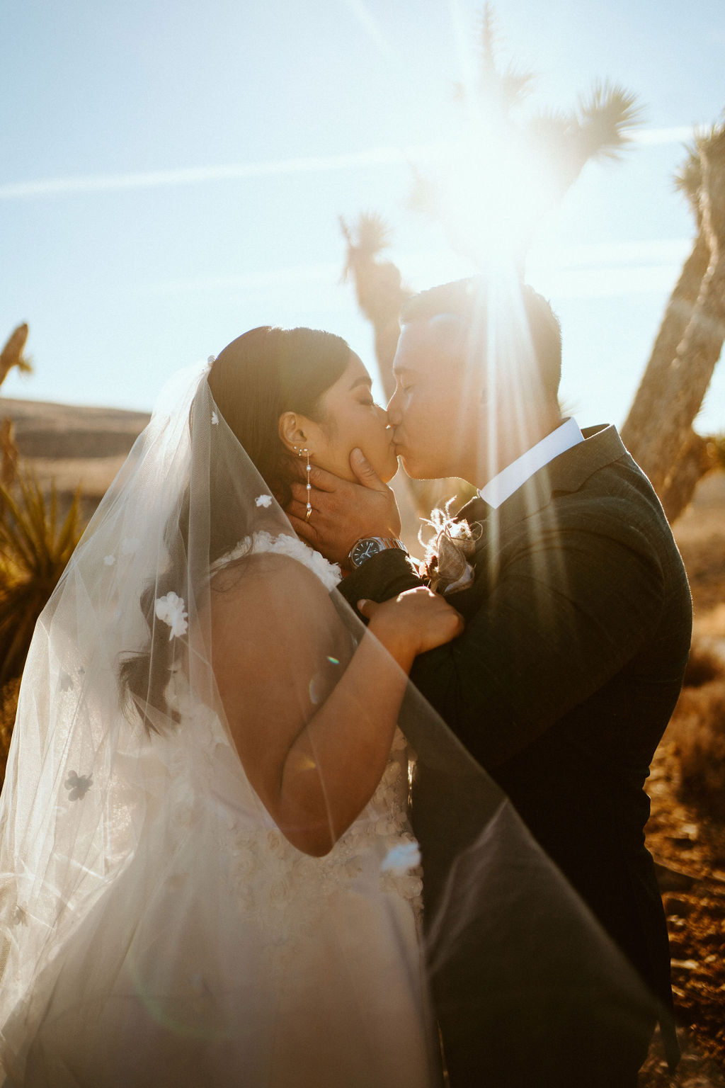 Bride and Groom Kissing as the sun rises behind them 