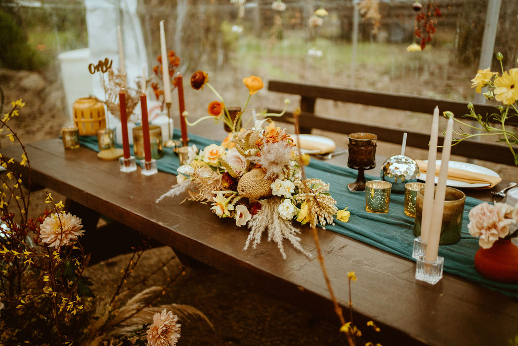 Close up sweetheart table of floral center piece, tapper candles, votives, amber gablets, and disco ball cups 