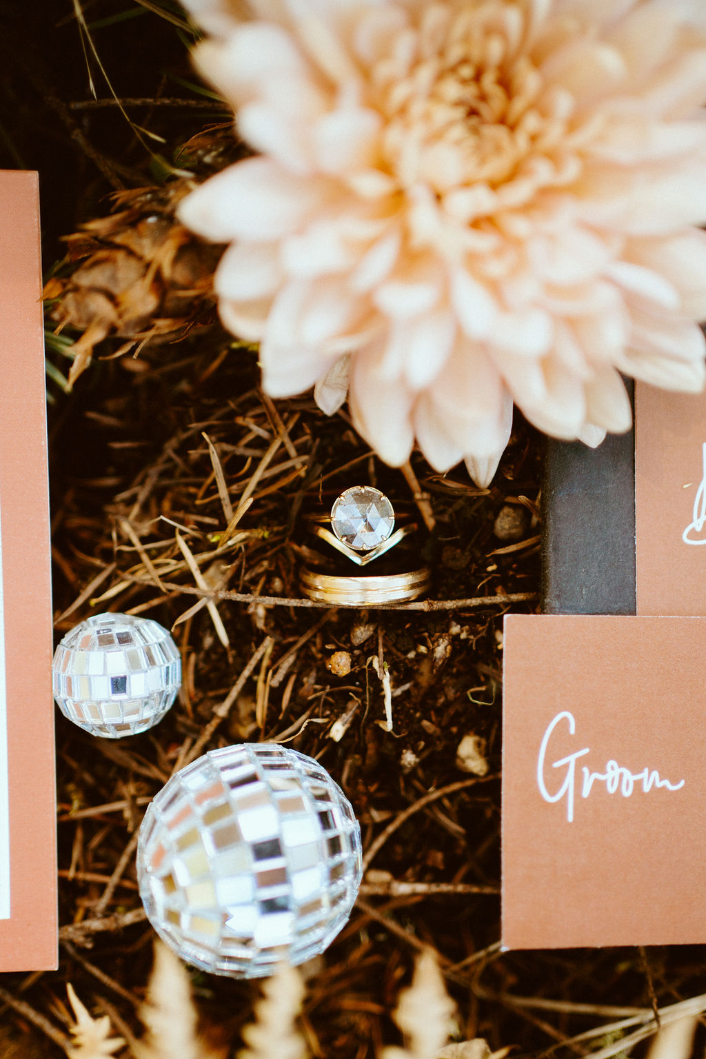 The bride and grooms rings surrounded with flowers and miniature sized disco balls 