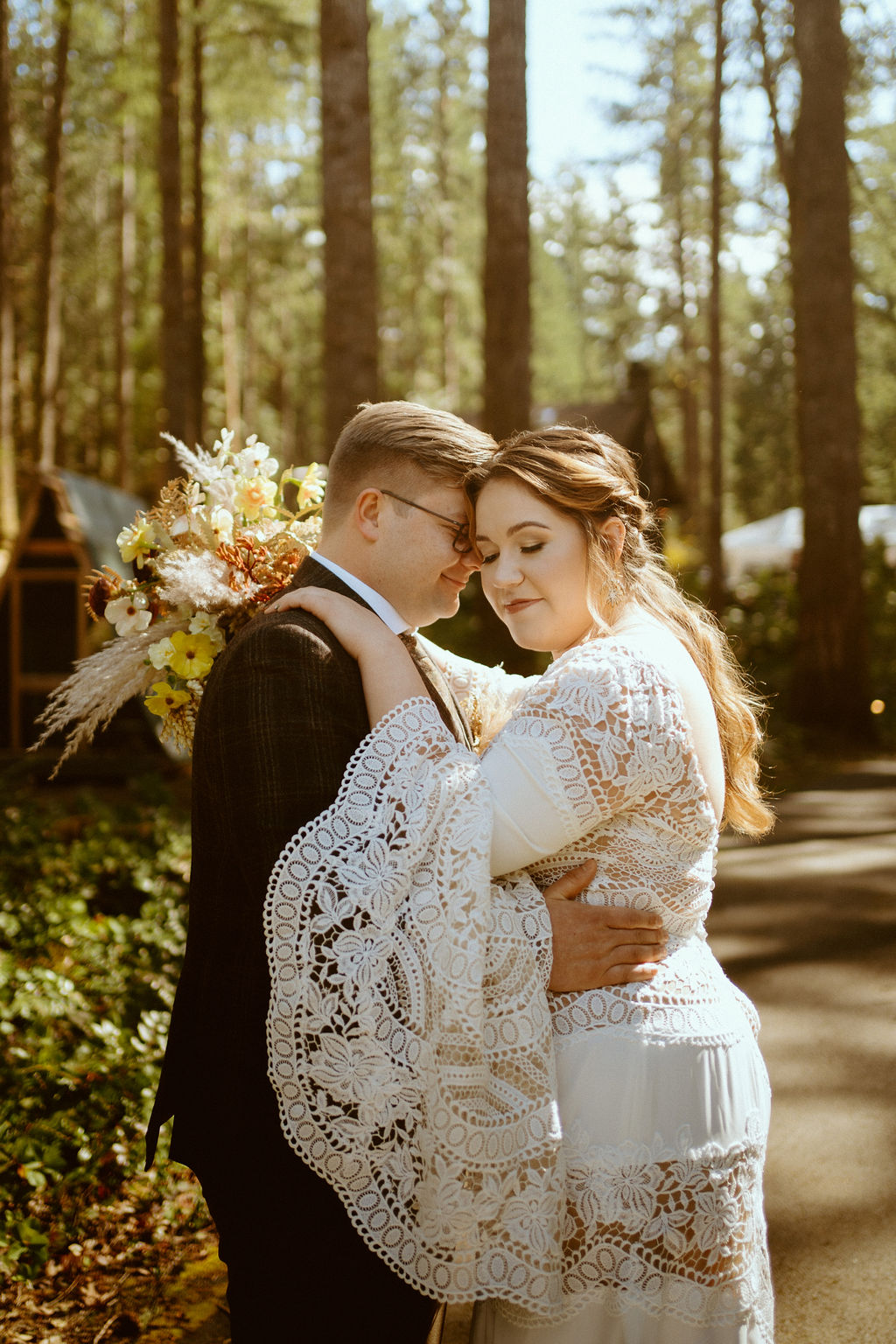 The couple poses on the side of the road with the bride facing the camera and the groom gently resting his head on her head