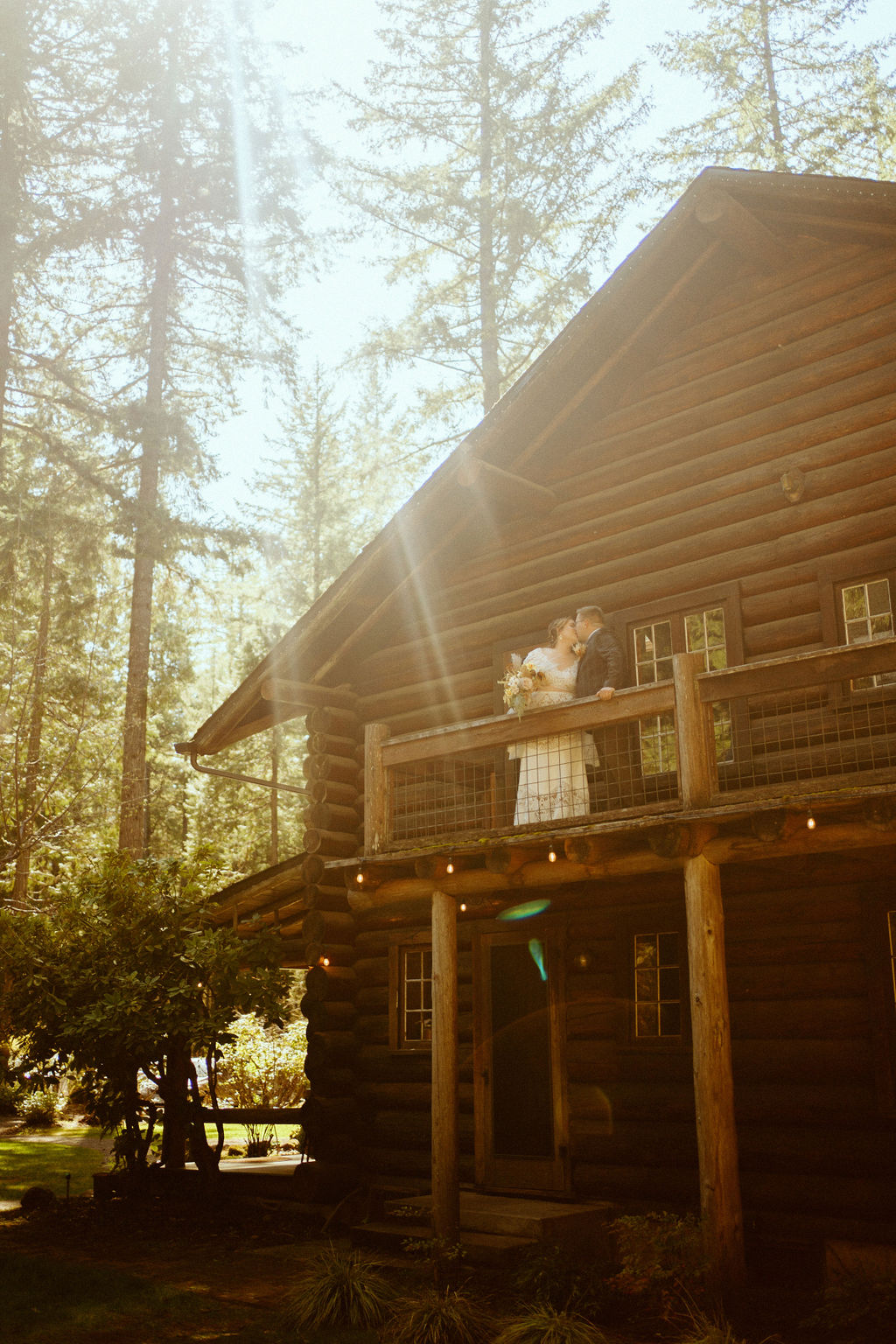 The bride and groom kissing on the balcony of this rustic cabin at loloma lodge 