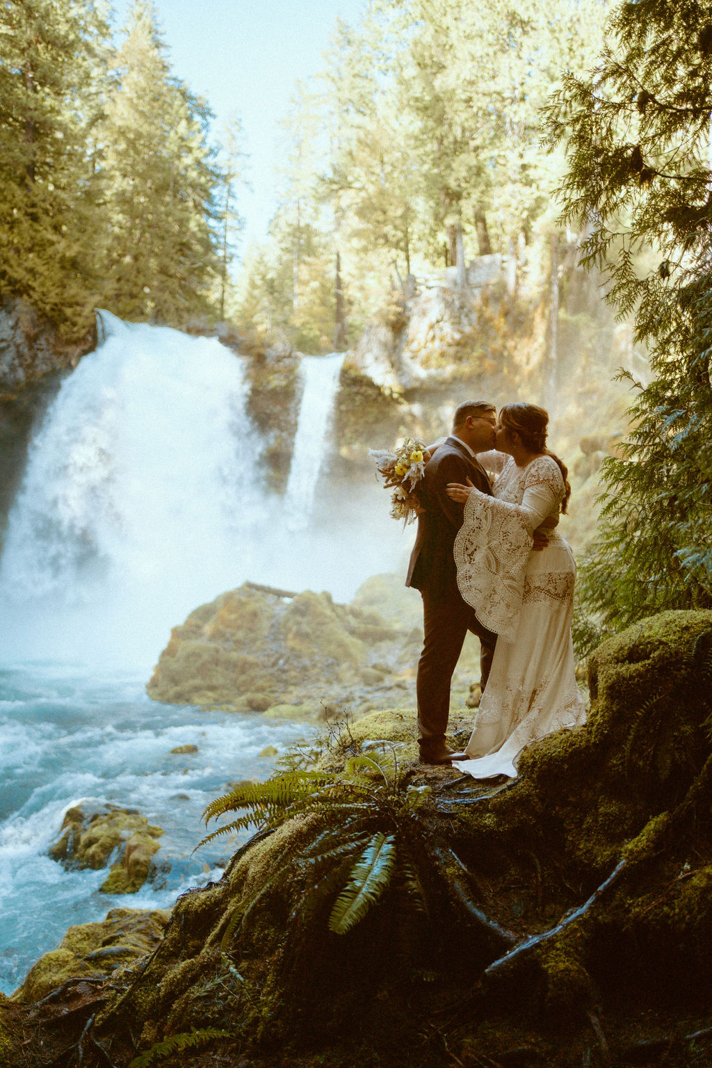 Loloma Lodge Retro Whimsical Micro-Wedding. The couple standing on the rock beds over looking the McKenzie River 