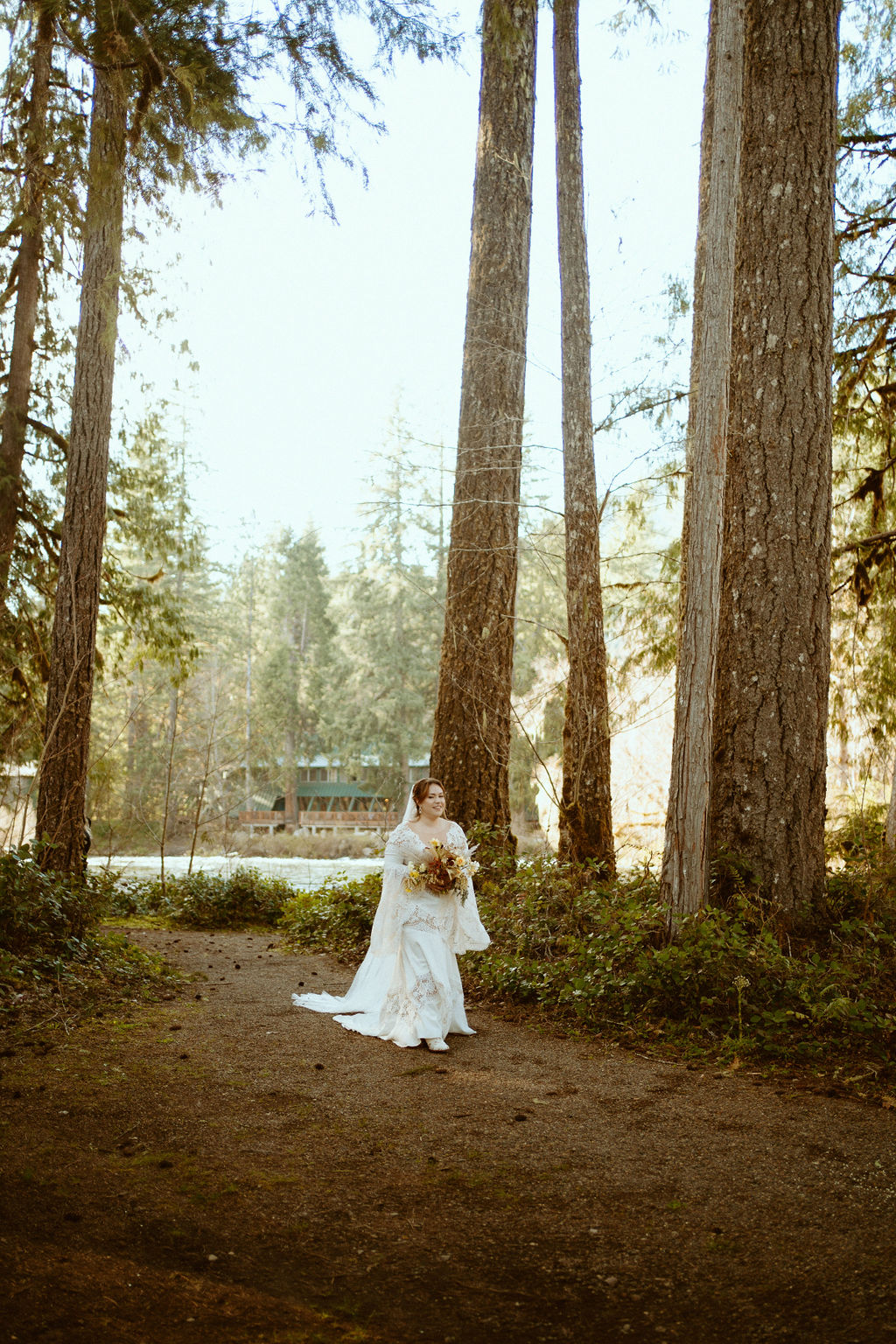 The bride walking down the aisle in a long sleeve lace wedding dress with a long veil holding her bouquet 