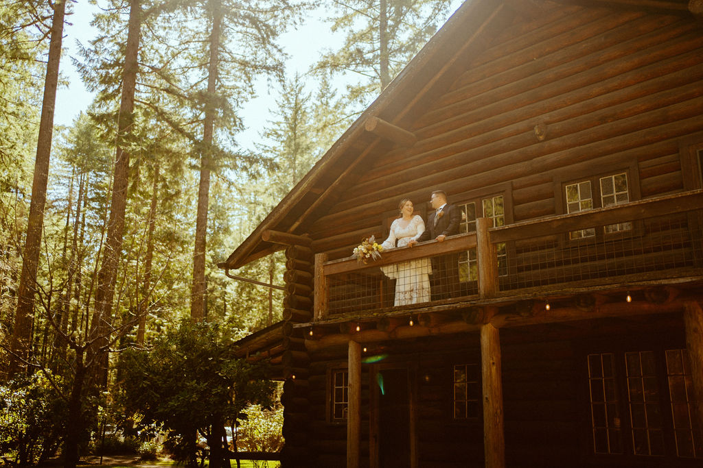 Loloma Lodge Retro Whimsical Micro-Wedding. Couple up on the balcony of the gorgeous rust lodge looking down into the forest of Oregon.  