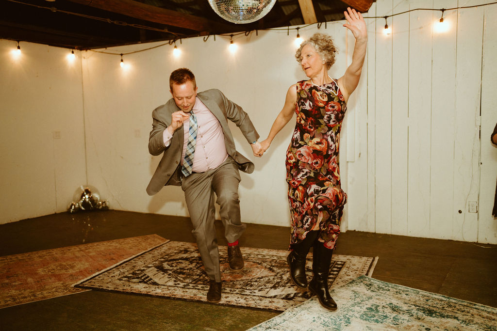 Family of the couple dancing to music at Loloma Lodge in a cute rustic room with bright lights, disco balls, and beautiful bohemian rugs.  