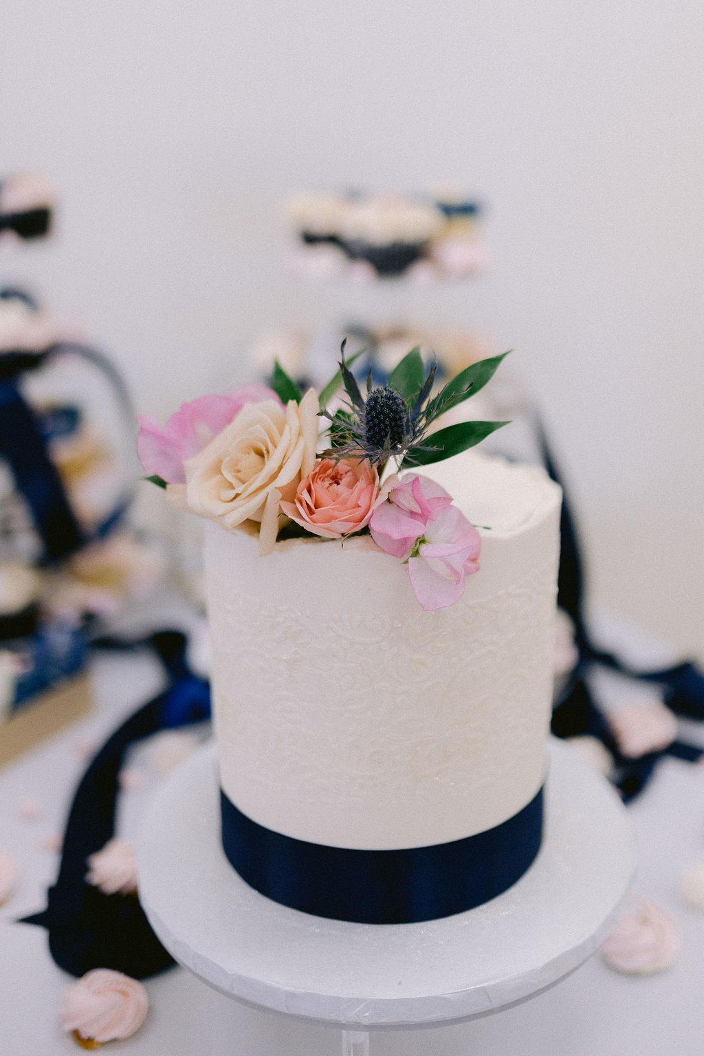 Navy Blue & Blush Pink Micro-Wedding close up of the single tier wedding cake with a simple navy blue ribbon. 