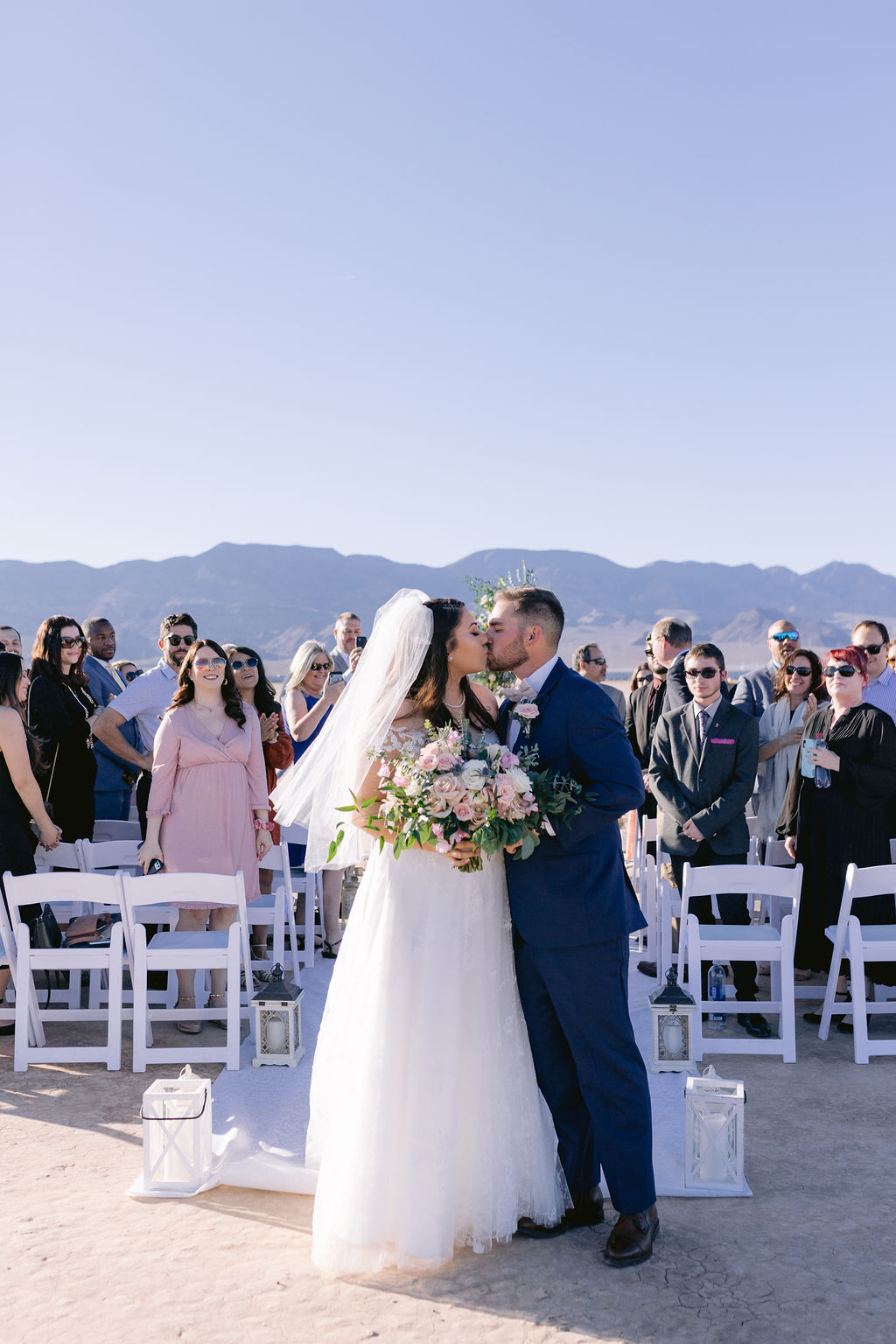 Navy Blue & Blush Pink Micro-Wedding sharing a kiss at the end of the isle while the guests cheer. 