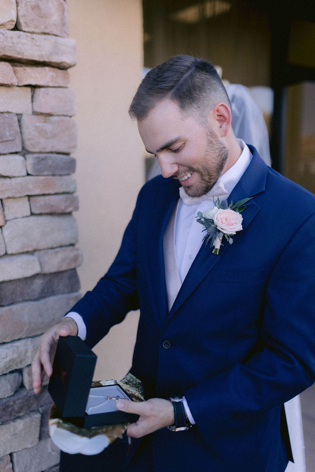 Groom smiles as he opens a small gift from the bride before the ceremony. 