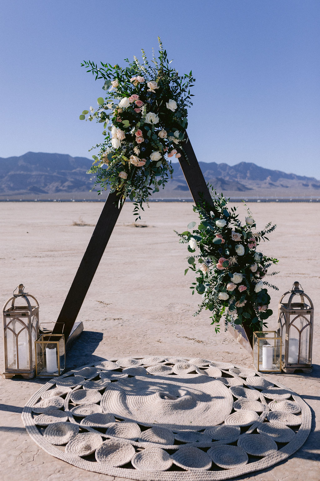 Close up of the large triangle floral arch with unique carpet and lanterns for the wedding ceremony. 