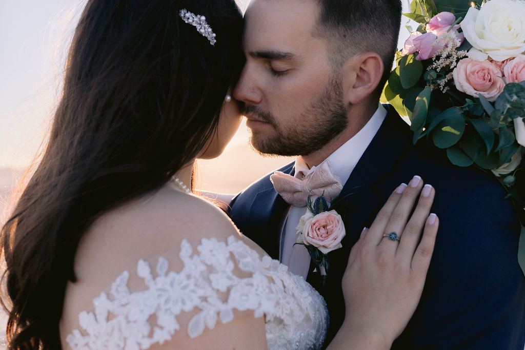 Navy Blue & Blush Pink Micro-Wedding Groom presses against the brides cheek his eyes closed as her hand is on his heart. 