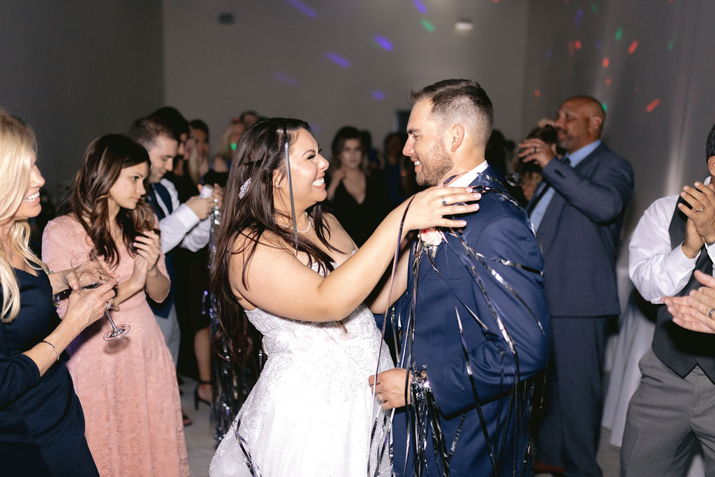 Navy Blue & Blush Pink Micro-Wedding Bride and groom are covered in streamers as they gaze at each other laughing. 