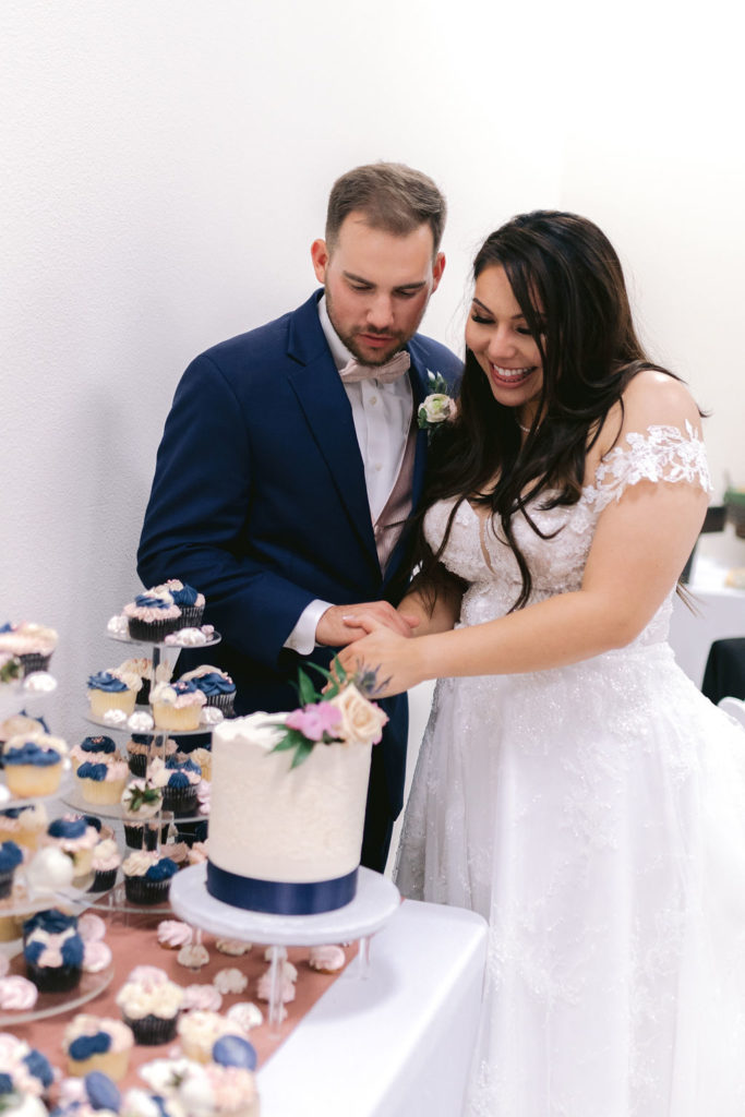 Navy Blue & Blush Pink Micro-Wedding bride and groom cutting into their wedding cake. 