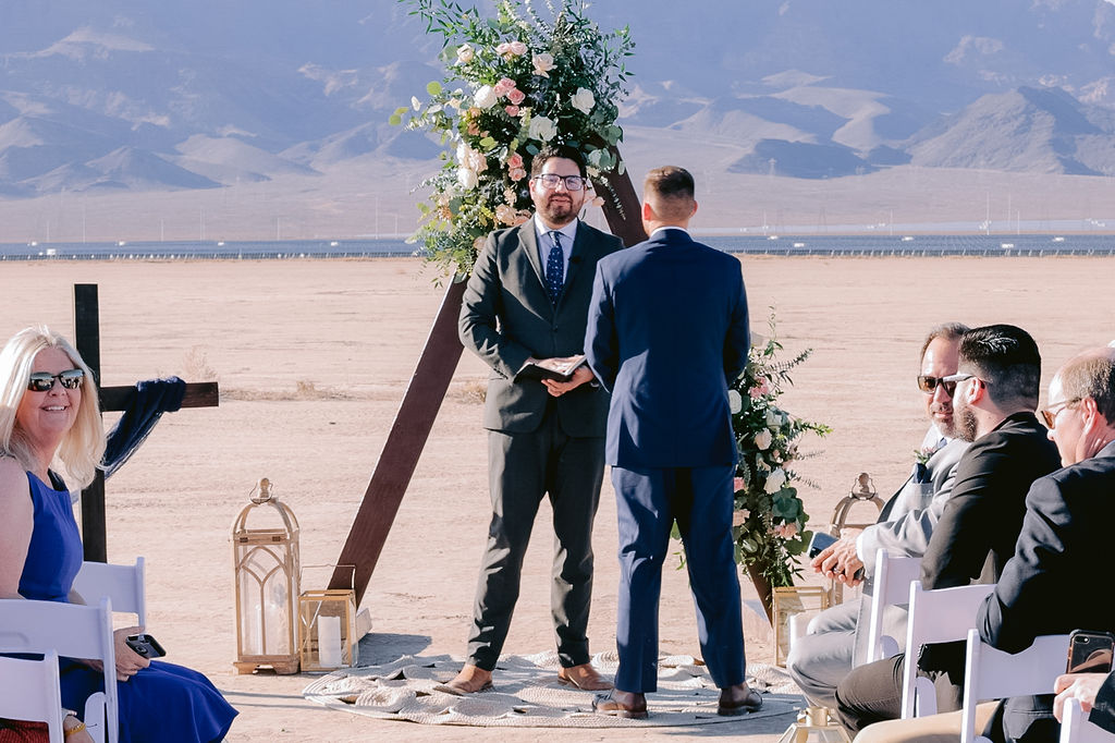 Navy Blue & Blush Pink Micro-Wedding Groom standing at the alter with officiant his back turned away from the isle. 