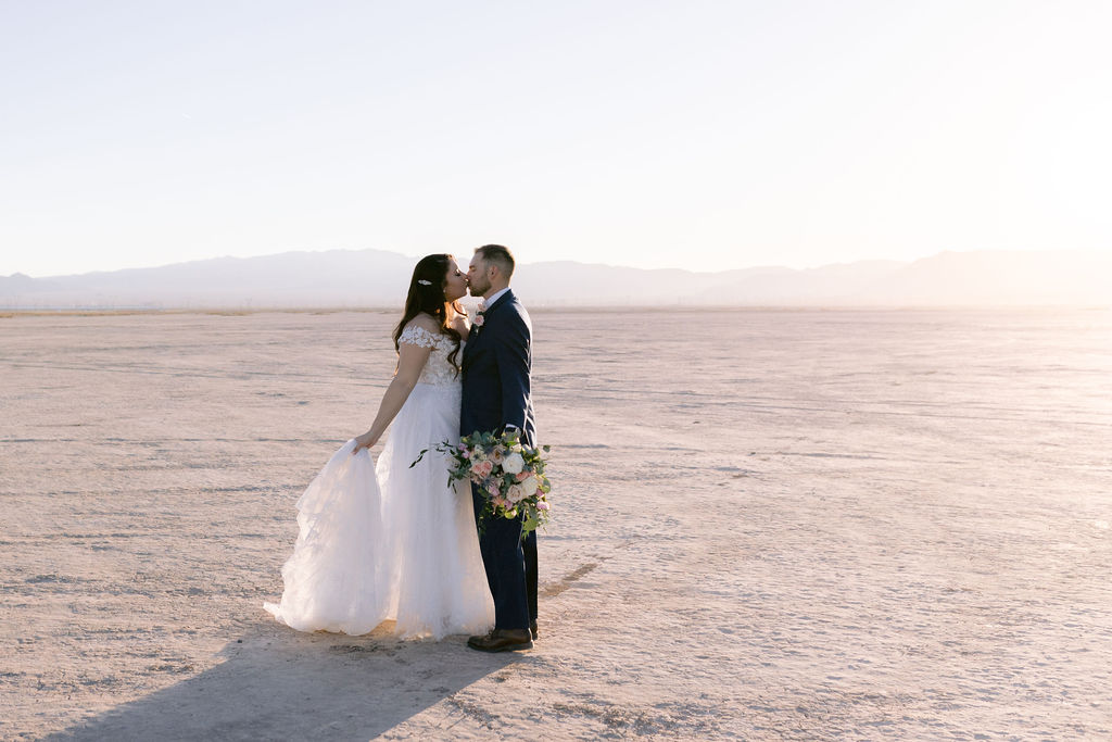 Navy Blue & Blush Pink Micro-Wedding further out shot of the bride and groom standing in the desert sunset. 