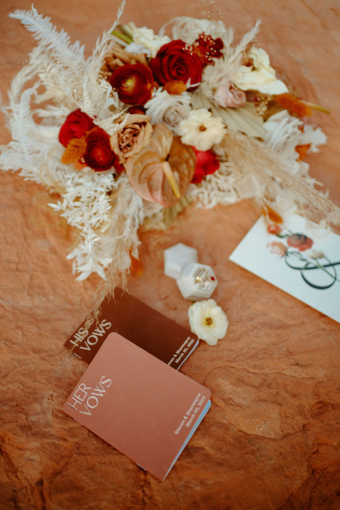 Romantic Mauve & Desert Hues Elopement bouquet with cream. white, reds, and golden hues. Their vow books and ring holder. 