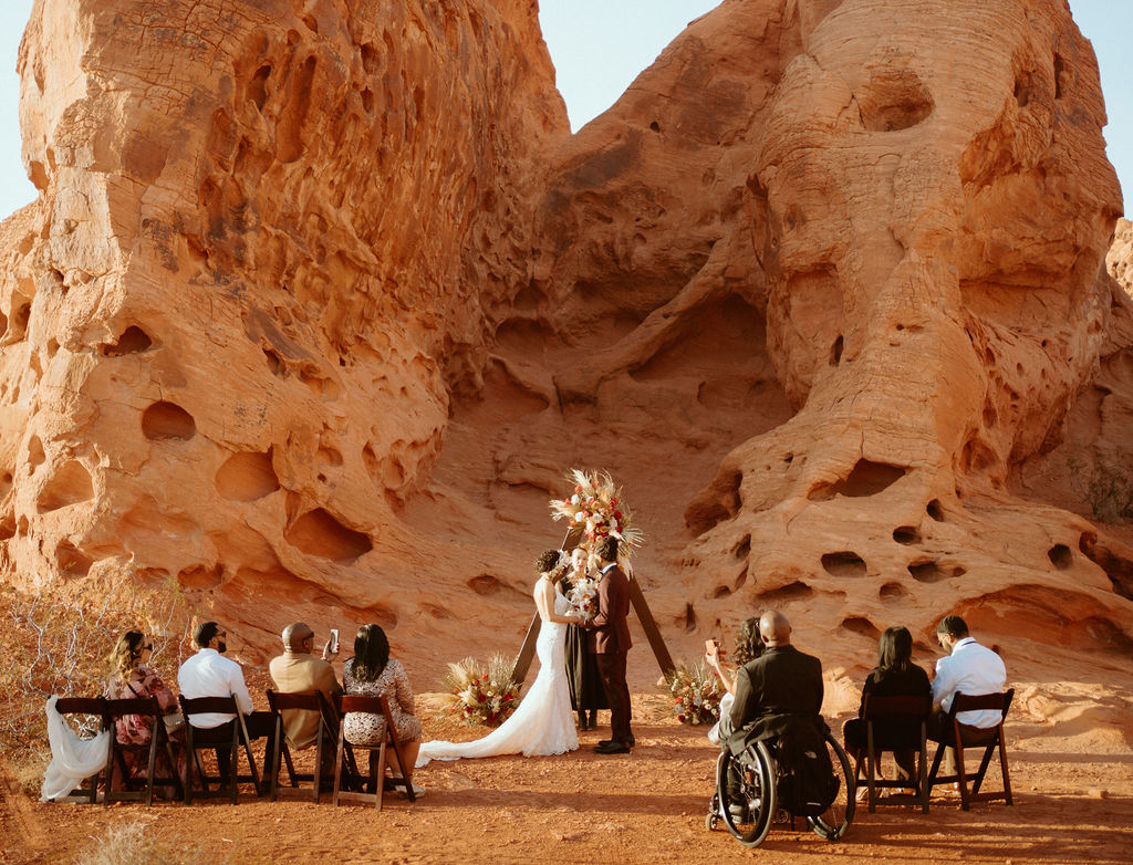Romantic Mauve & Desert Hues Elopement ceremony has begun. A beautiful red rock mountain as the backdrop. 