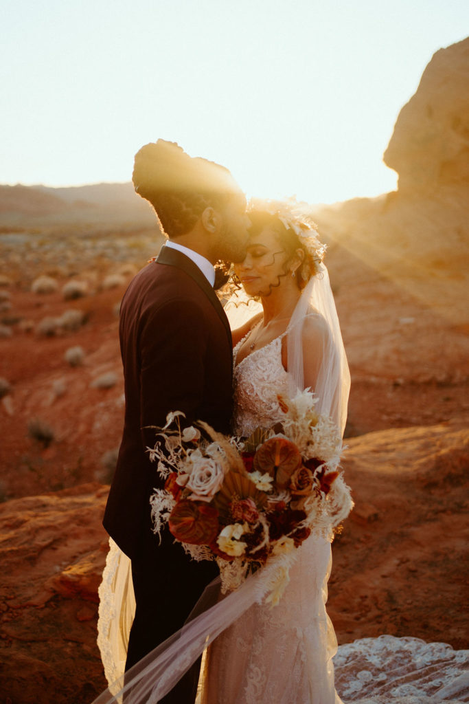 Sunset at the valley of fire with groom kissing his brides forhead. 