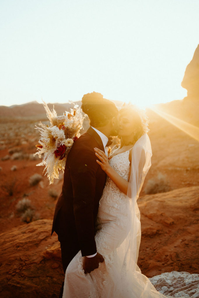 Romantic Mauve & Desert Hues Elopement Groom kissing his bride with the desert sunset. 