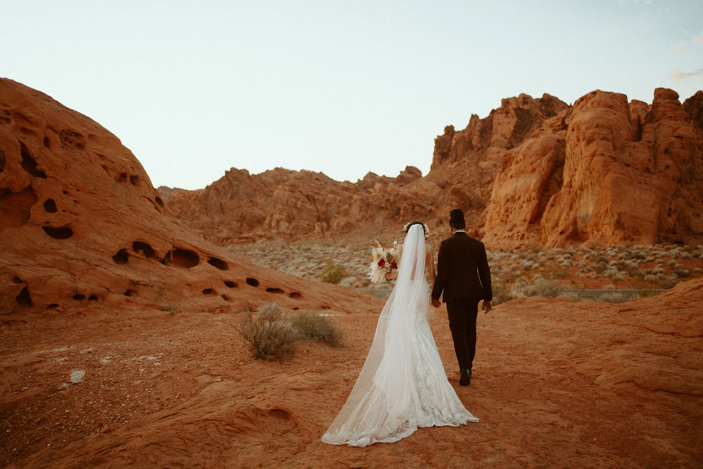 Romantic Mauve & Desert Hues Elopement Bride and groom walking towards the Seven Sisters in Valley of Fire. 