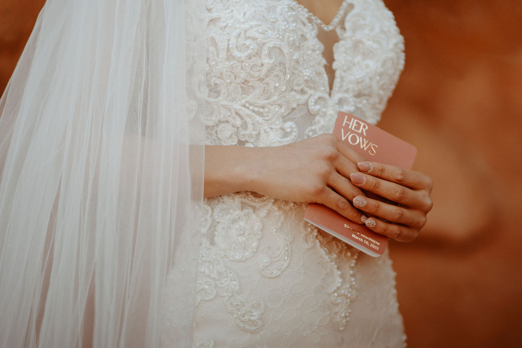 Close up of brides gown with her personal vow book in hand. 