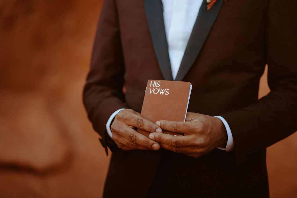 Close up of groom with personal vow book in hand. 