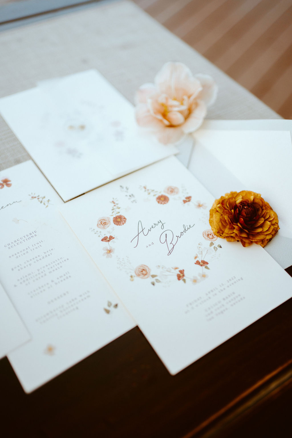 Rustic Boho Never Looked So Good! Close up of couples boho styled stationary focusing on the wedding invitation. With a boho styled flowered wreath around the couples name and the wedding details below. 