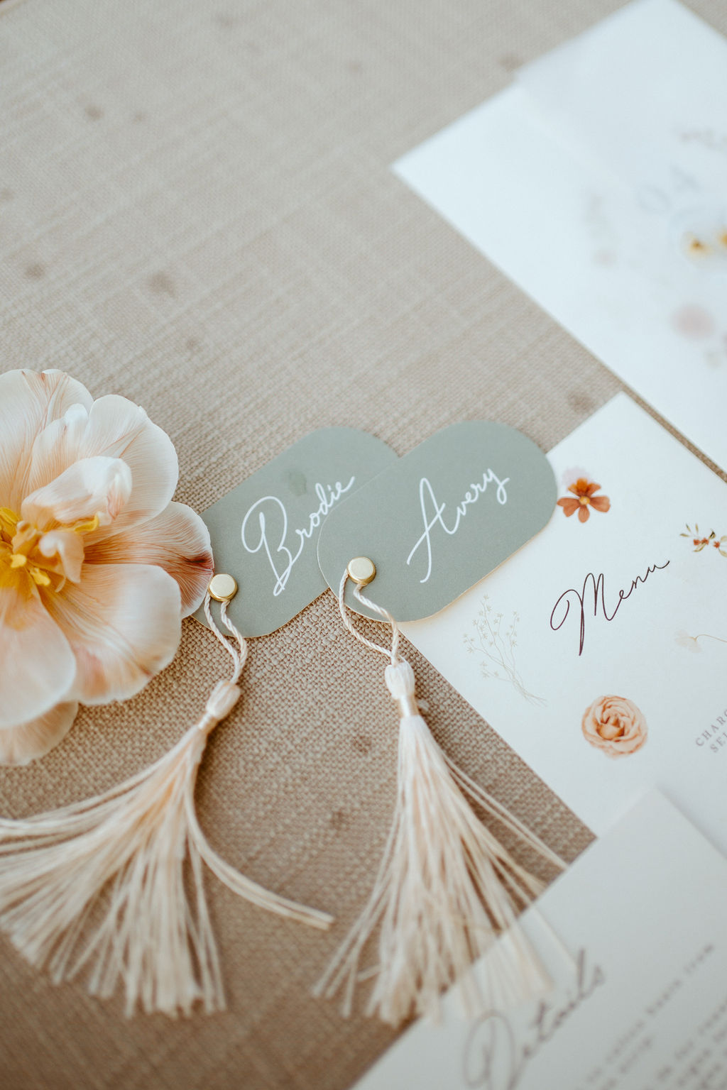 Close up of the couples name tag stationary. Their names written in a soft white cursive lettering on a grey tag with white tassel clasped on. 