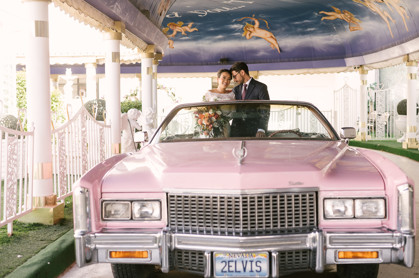 Two Bridal Outfits are Better than One! Newlyweds at the Little White Wedding Chapel in Las Vegas in the back seat of Elvis Presley's famous pink Cadillac 