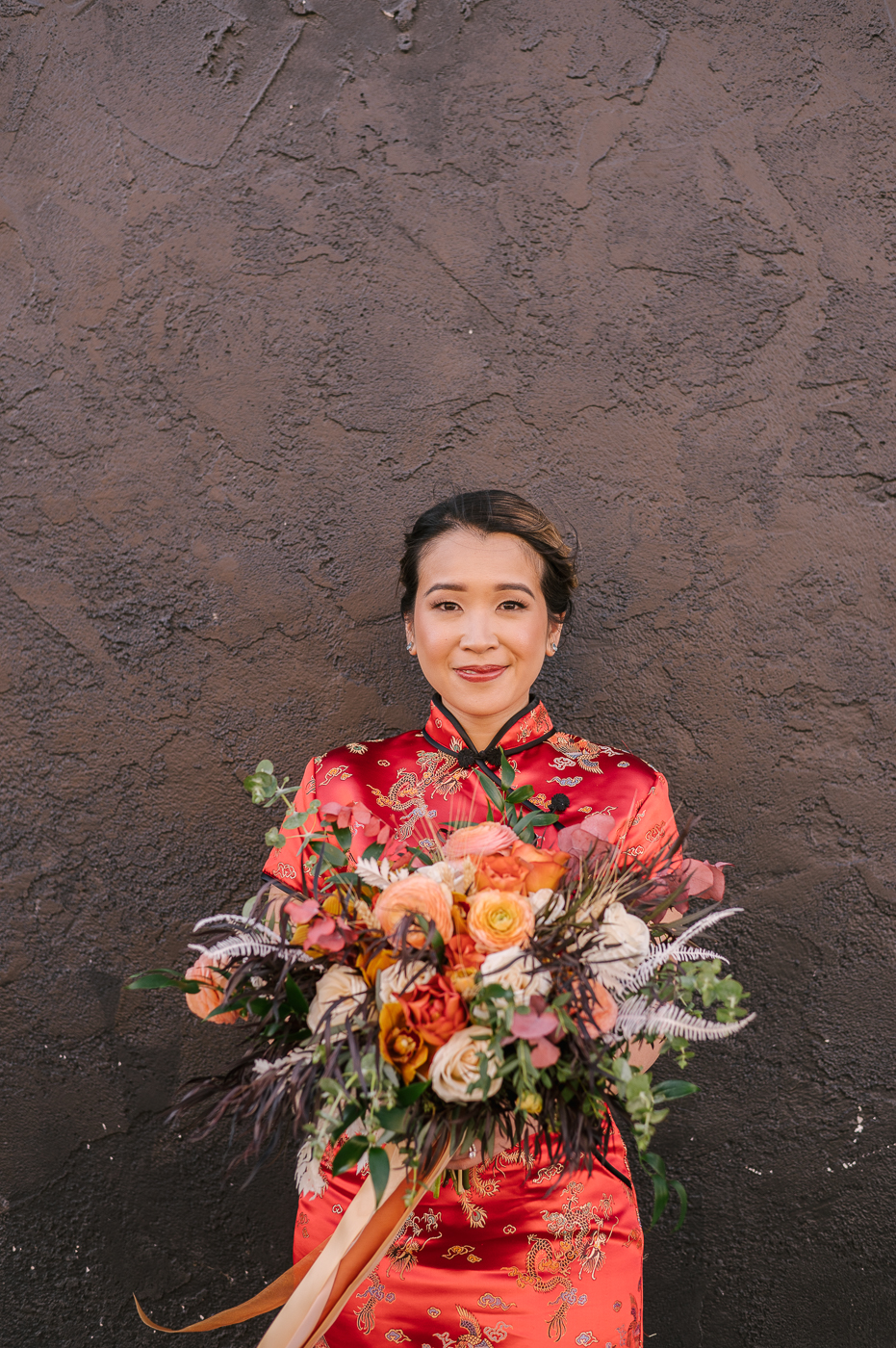 Two Bridal Outfits are Better than One! The beautiful bride in her traditional red cheongsam wedding dress holding her bouquet