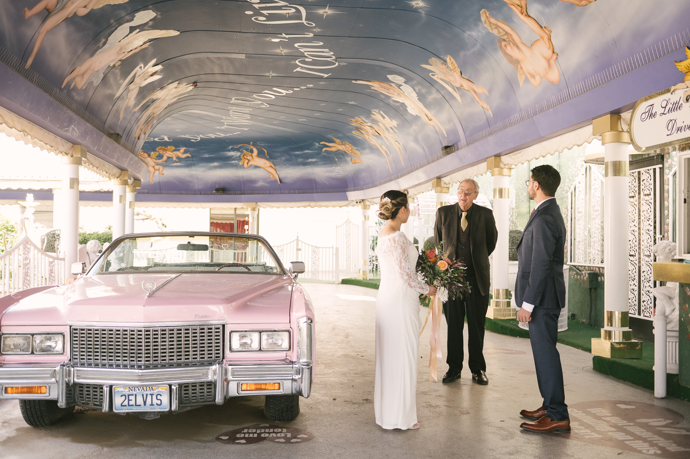 Newlyweds get married in the driveway of the Little White Wedding Chapel next to the Elvis's famous pink Cadillac. 