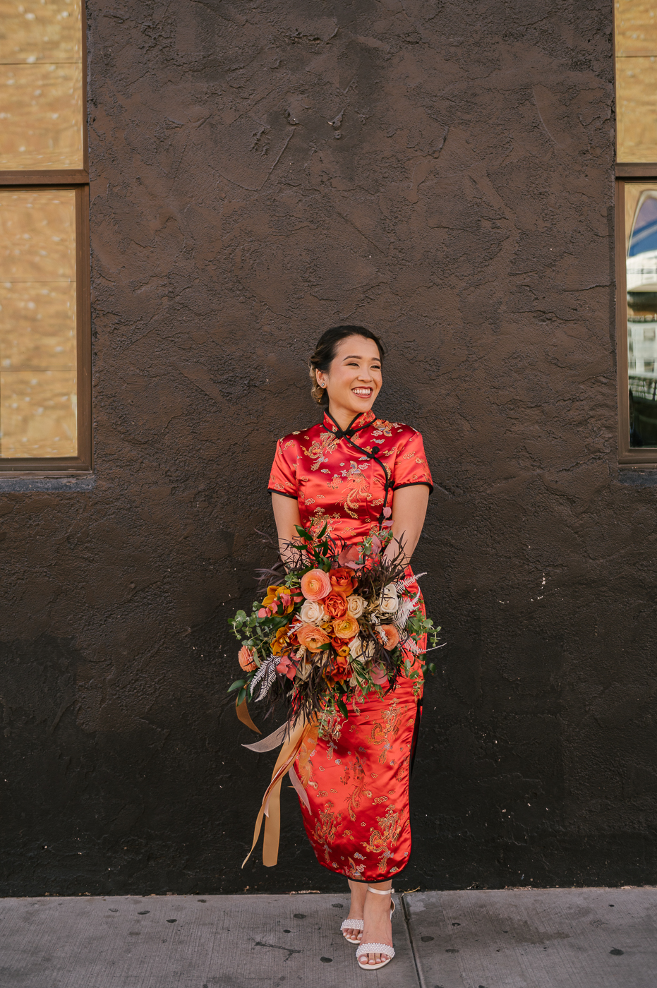 Bride in a traditional cheongsam with her wedding bouquet that compliment the red in her dress. 
